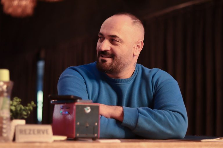 Casual portrait of a man in a blue sweater sitting indoors at a restaurant. — 3 Tips for Maintaining Proper Posture at Work