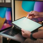 Designer using a digital pen on a tablet with colorful screens in a modern home office setting. — 4 Uses Of Cheap Cpanel Host
