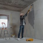 A man painting an interior wall with a roller during a home renovation project. — 5 reasons to choose a U-shaped kitchen