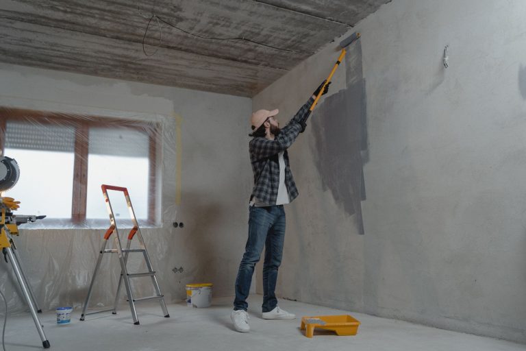 A man painting an interior wall with a roller during a home renovation project. — 5 reasons to choose a U-shaped kitchen