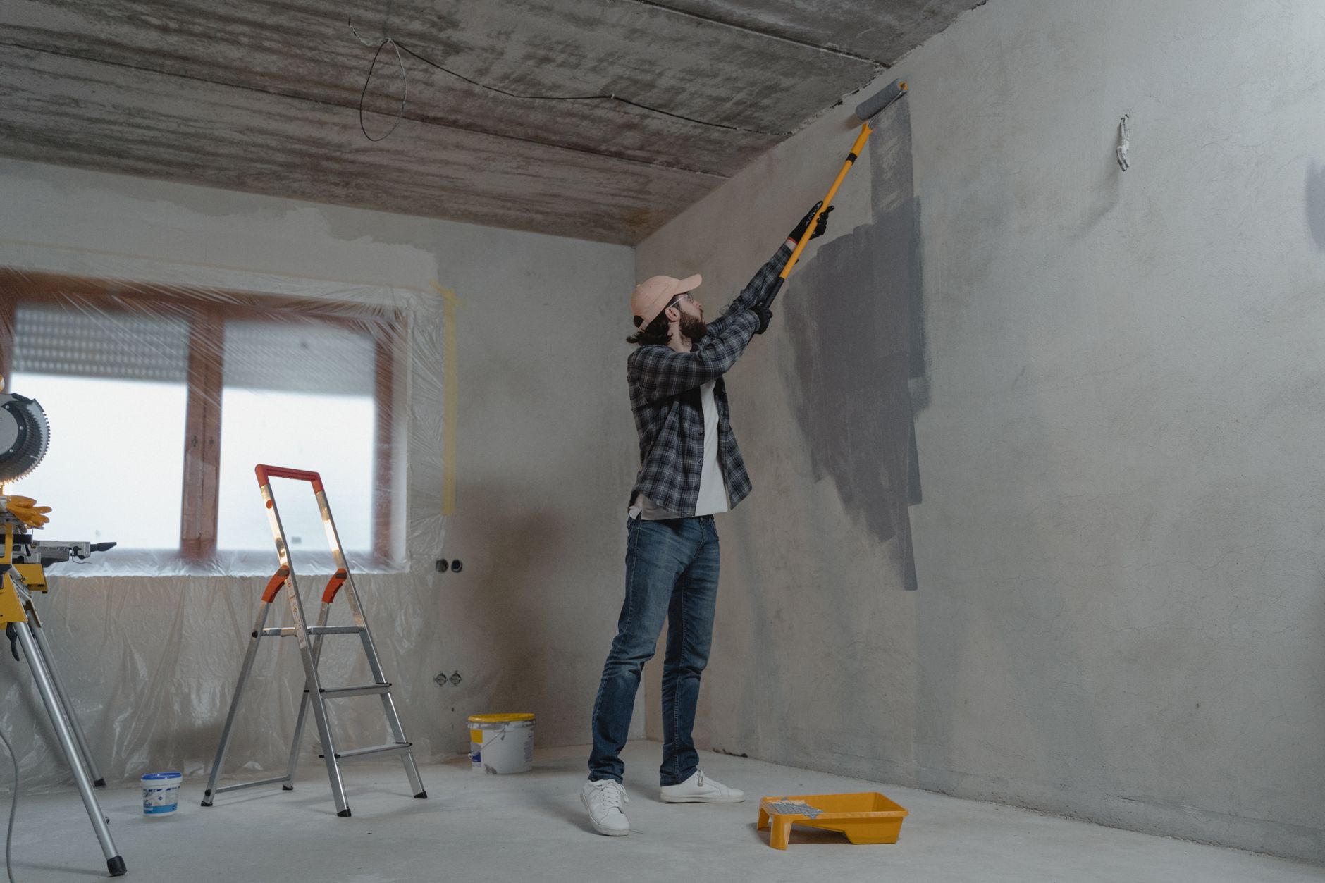 A man painting an interior wall with a roller during a home renovation project. — 5 reasons to choose a U-shaped kitchen