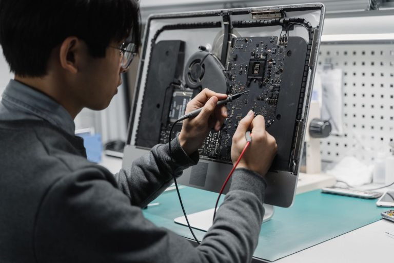 A technician works on a computer motherboard using tools at a workspace, focusing on electronics repair. — 8 Notable Features