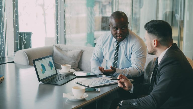 Two business professionals engaged in discussion over laptops and documents. — Always approach the budget friendly space thro