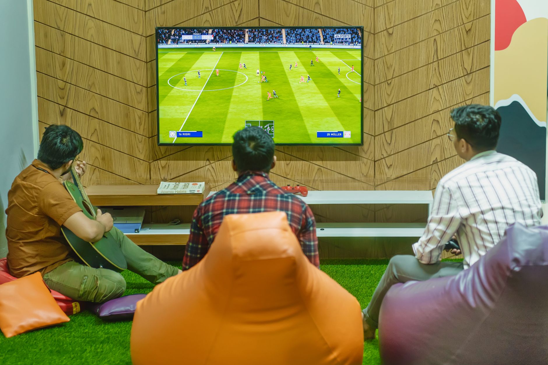 Three friends relaxing and playing a soccer video game indoors on a comfortable game night. — Be Knowledgeable With The Speci