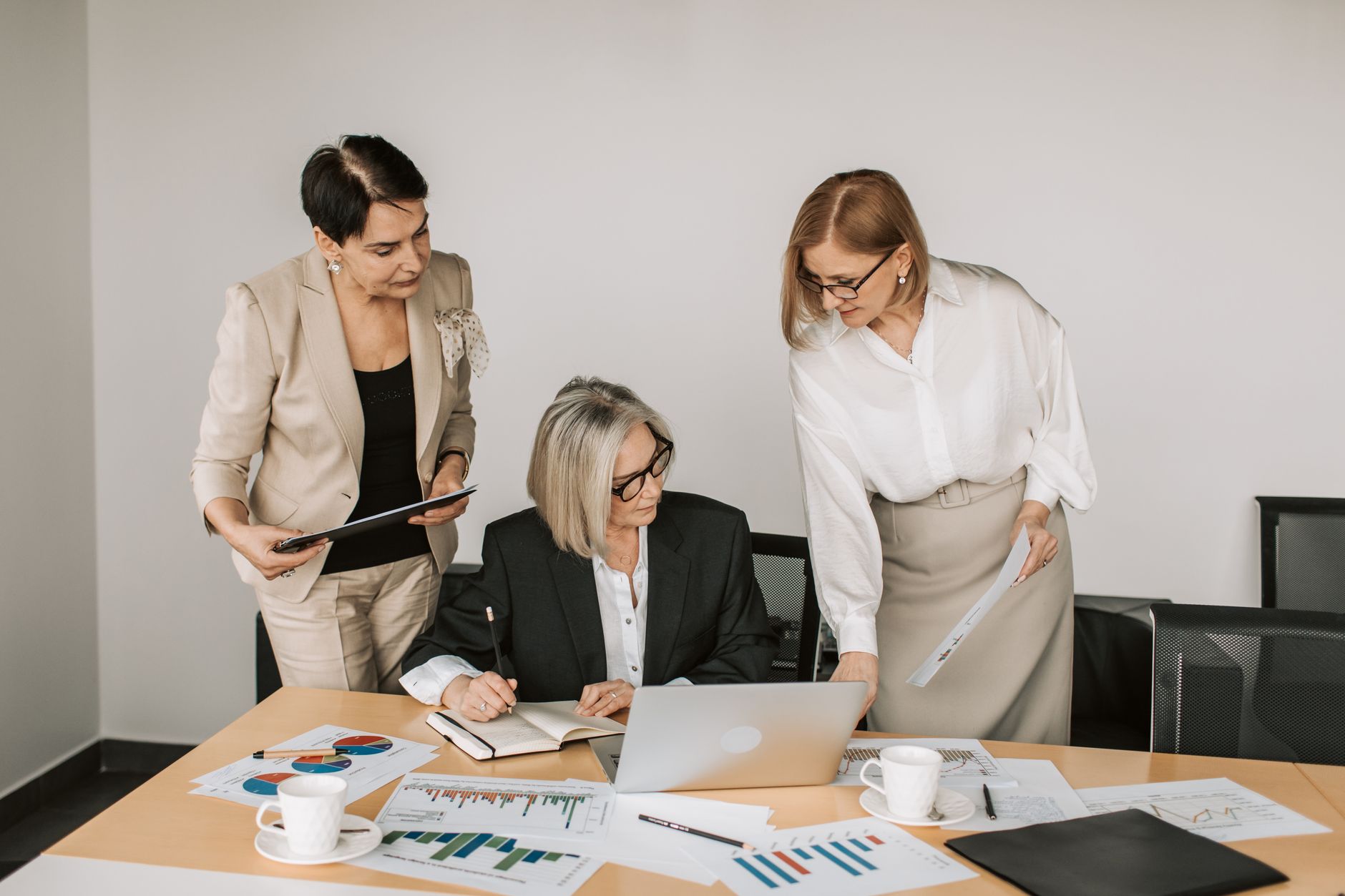 Three businesswomen discussing documents during a meeting in a modern office setting. — Become a Pro Player with These Essent