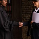 A lawyer in formal attire shakes hands with a client in a book-lined office. — Best of Brampton criminal defence lawyer