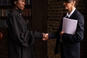 A lawyer in formal attire shakes hands with a client in a book-lined office. — Best of Brampton criminal defence lawyer