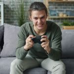 Young adult intensely playing video games on a couch in a cozy living room setting. — Casino Sites Known for Regulatory Compl