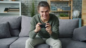 Young adult intensely playing video games on a couch in a cozy living room setting. — Casino Sites Known for Regulatory Compl