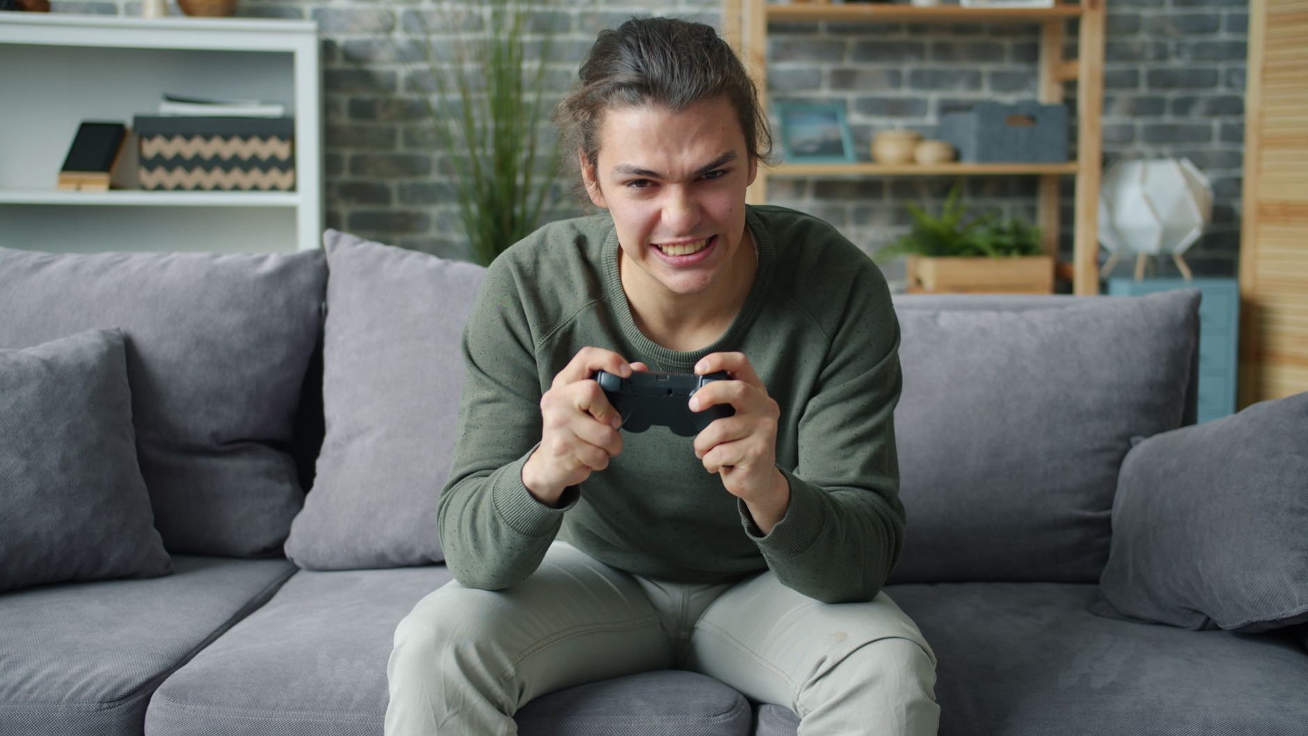 Young adult intensely playing video games on a couch in a cozy living room setting. — Casino Sites Known for Regulatory Compl