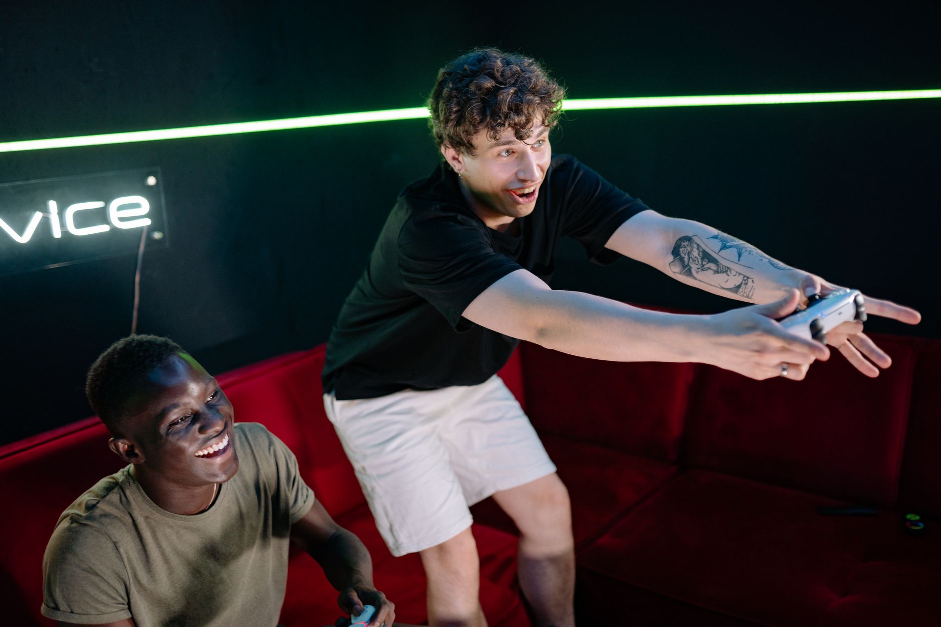 Two young men having fun playing video games in a cozy indoor setting. — Chronicles of Triumph: Lsm99 Casino's Epic Tales of