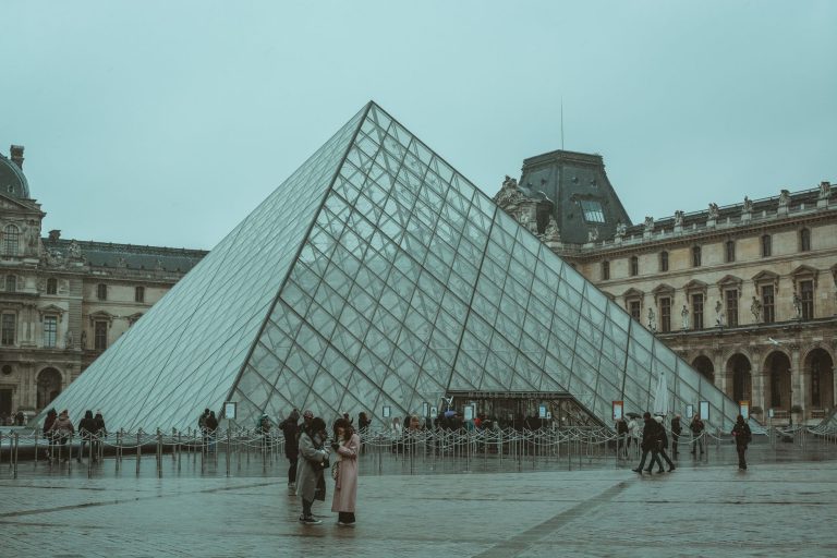 A winter day at the iconic Louvre Museum pyramid in Paris, capturing tourists and the architectural beauty. — Comprehensive G