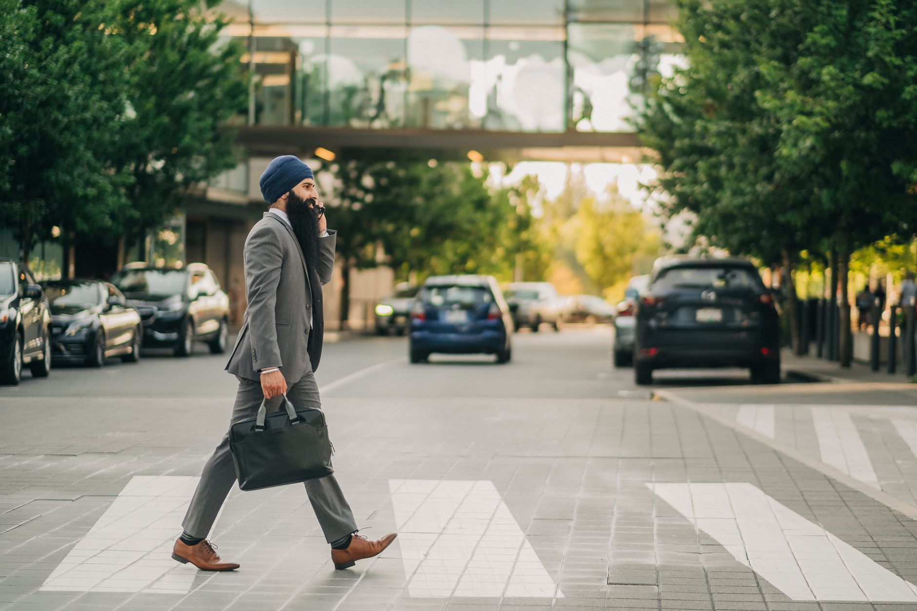 Sikh businessman with a turban crossing a city street on a zebra crossing, carrying a briefcase. — Cool Down Your Summer Heat