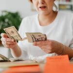A woman sits indoors counting cash at her office desk, focusing on finances. — Do not get anxious with the failure