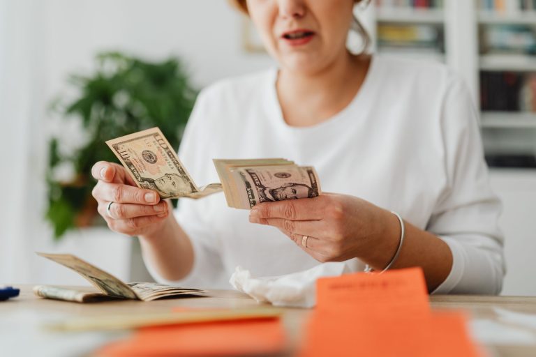 A woman sits indoors counting cash at her office desk, focusing on finances. — Do not get anxious with the failure