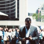 Focused businessman using tablet in a bustling crowd in Toronto's busy urban setting. — Do's and Dont's of B2B SaaS cold call