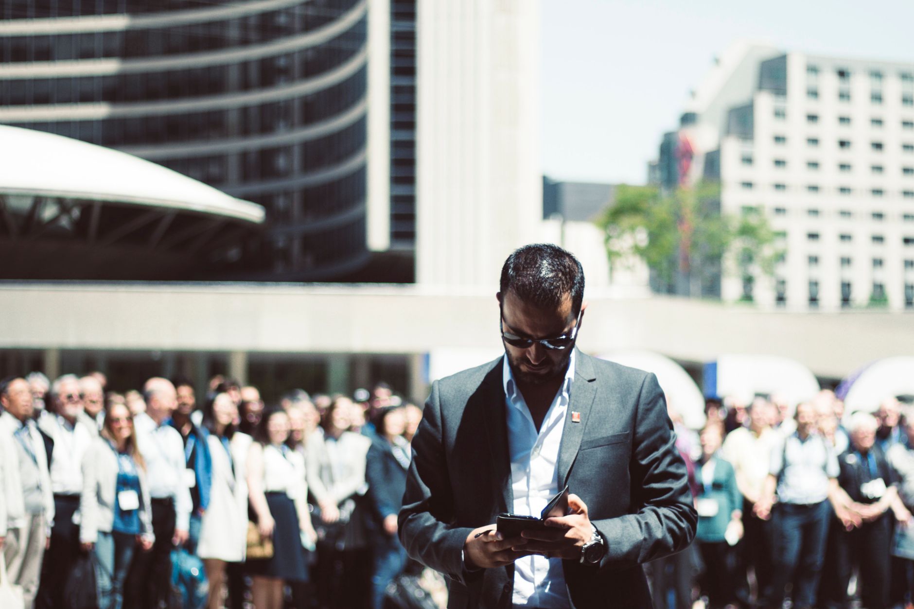 Focused businessman using tablet in a bustling crowd in Toronto's busy urban setting. — Do's and Dont's of B2B SaaS cold call