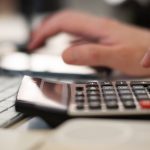Close-up of hands using a calculator and keyboard in a financial setting, indoors. — Do you know the best ways how to make mo