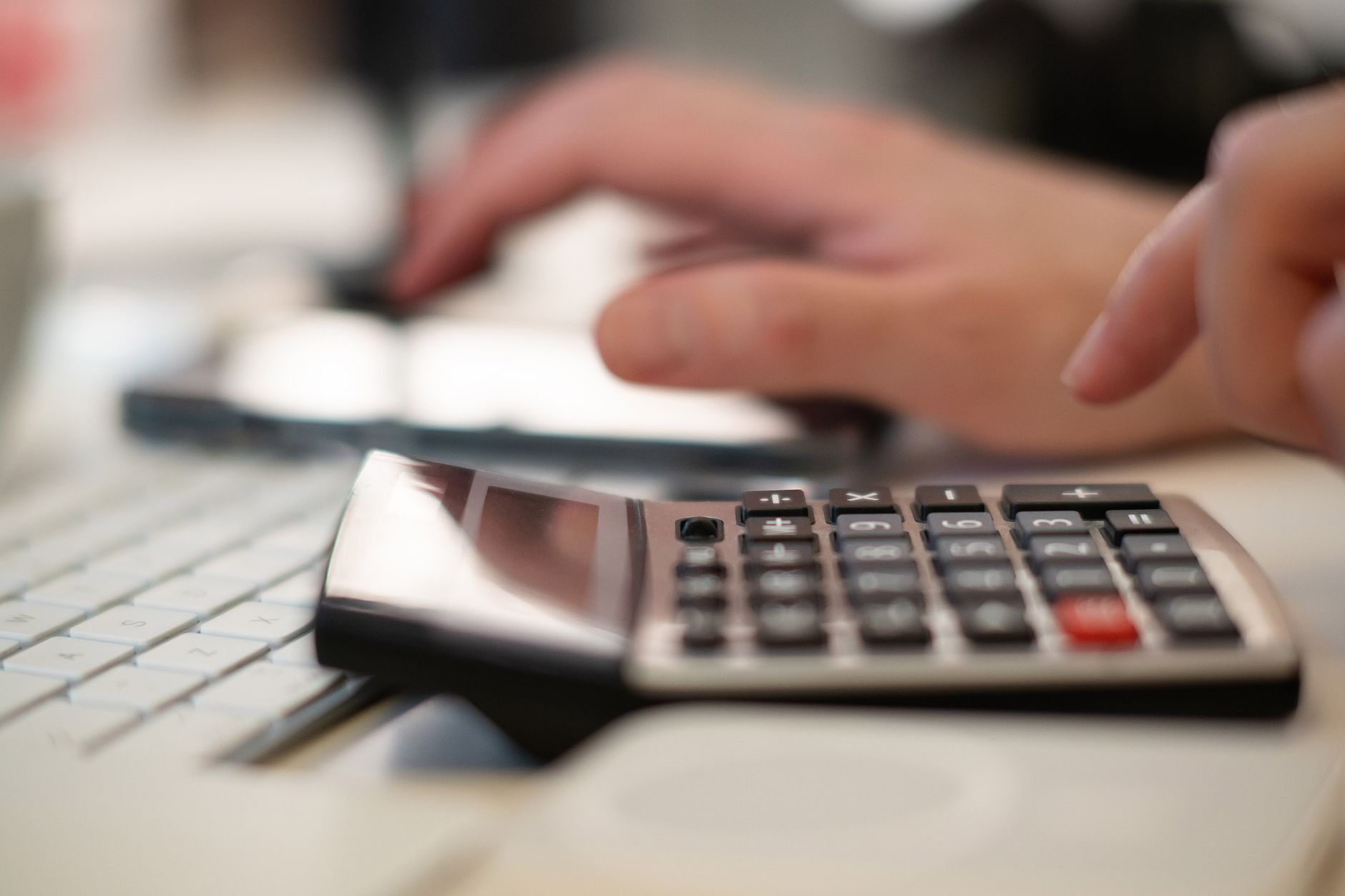 Close-up of hands using a calculator and keyboard in a financial setting, indoors. — Do you know the best ways how to make mo