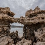 A striking coastal rock formation displaying natural erosion against a cloudy backdrop by the sea. — Download the baazi247 ap