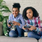 Two teenagers playing video games together on a comfortable couch, surrounded by indoor plants. — Enjoy Casino Games Galore a