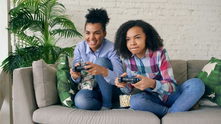 Two teenagers playing video games together on a comfortable couch, surrounded by indoor plants. — Enjoy Casino Games Galore a