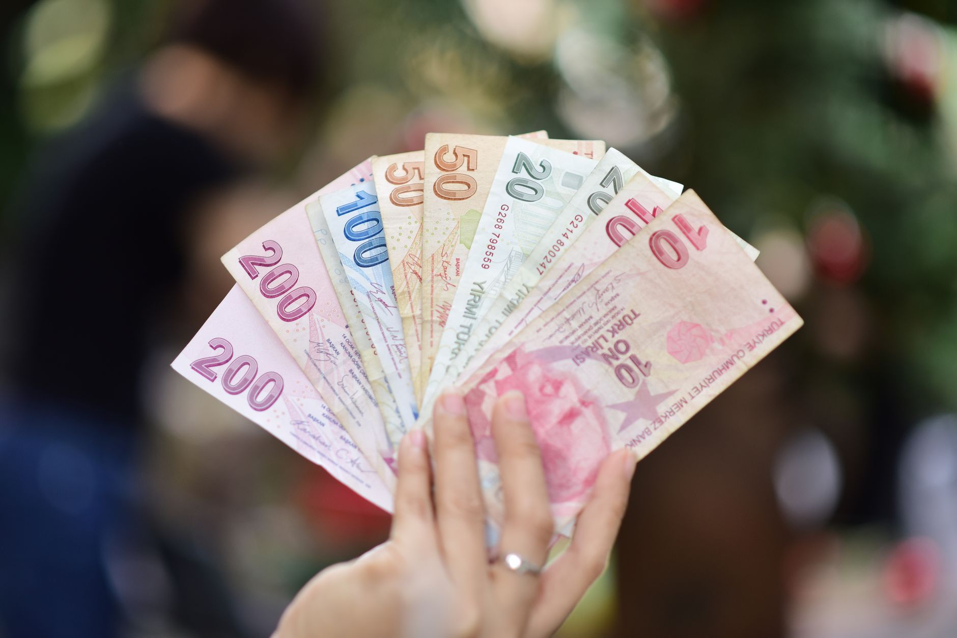 Hand holding multiple denominations of Turkish Lira banknotes outdoors. — Five Most Expensive Places to Buy Property in North