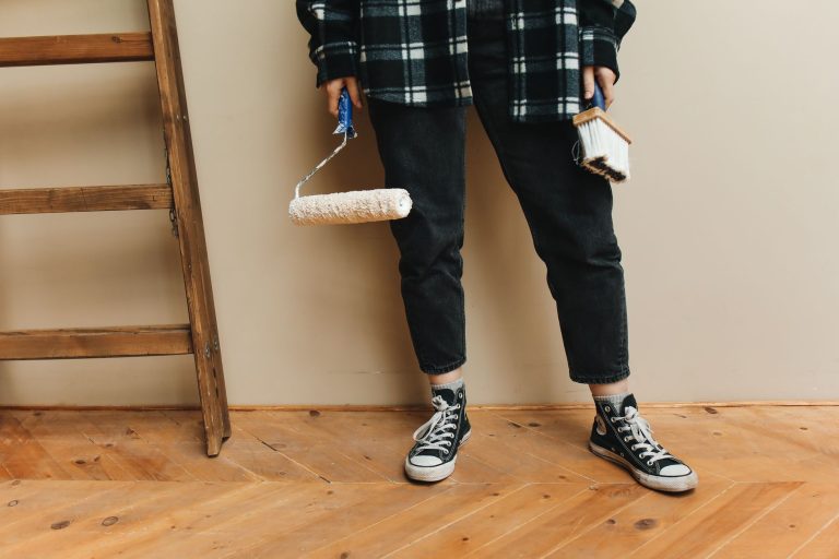 A person holding a paint roller and brush during a home renovation project. — Four Tips For Maintaining Solar Panels