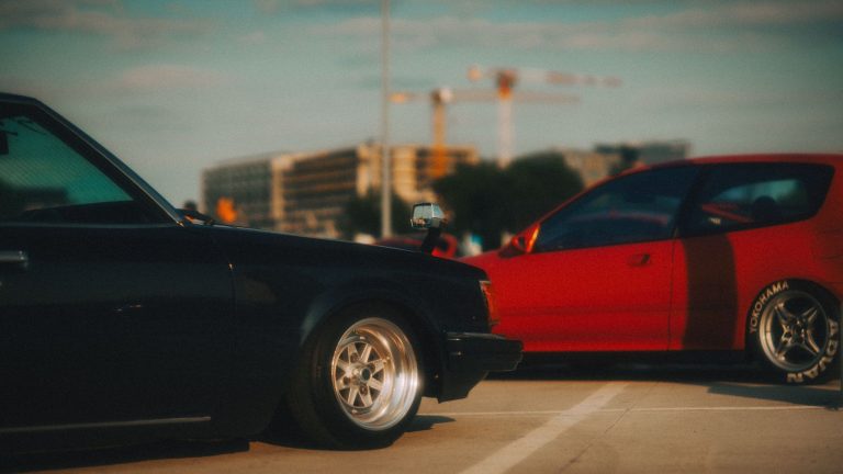 A nostalgic view of classic cars parked in a city lot, captured at sunset. — Four Tips to Get The Best Rental Luxury Car