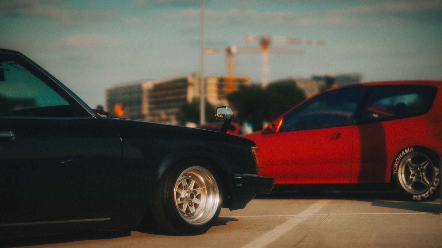 A nostalgic view of classic cars parked in a city lot, captured at sunset. — Four Tips to Get The Best Rental Luxury Car