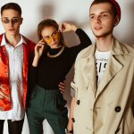 Fashionable portrait of three adults showcasing trendy outfits and accessories indoors. — Get Decorated With Gildan G500 Whol