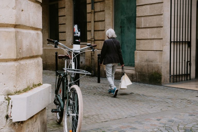 A city street with a bicycle and person walking down a cobblestone path. — Gifting Coffee Mugs from Namshi throughout the Yea