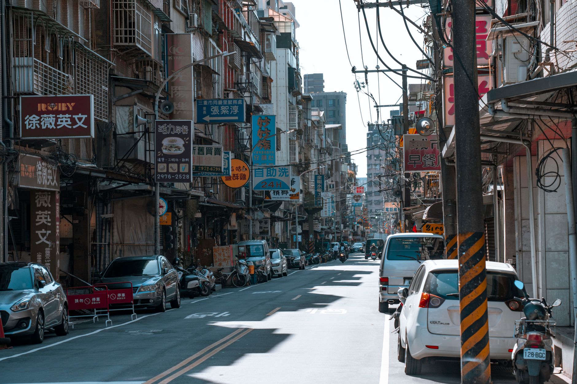 A busy street lined with cars and various colorful business signs on a sunny day. — High-Quality Replica Designer Handbags fo