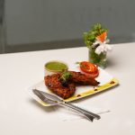 Tantalizing plate of grilled chicken with vibrant green chutney and fresh garnishes. — Homemade Nut Butters At Less Cost
