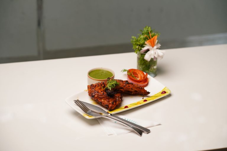 Tantalizing plate of grilled chicken with vibrant green chutney and fresh garnishes. — Homemade Nut Butters At Less Cost