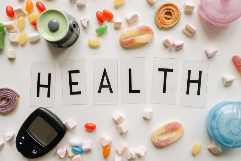 Creative flat lay with sweets around a 'HEALTH' text and monitoring device, symbolizing diabetes awareness. — How can I remov