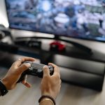 Close-up of hands holding a gaming controller while playing video games indoors. — How to Baccarat Myths in Baccarat?