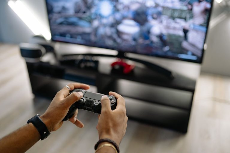 Close-up of hands holding a gaming controller while playing video games indoors. — How to Baccarat Myths in Baccarat?