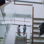 Aerial view of professionals conversing in a glass staircase in a modern office. — How to build a virtual sales team for dyna