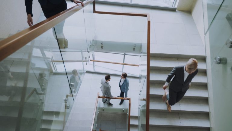 Aerial view of professionals conversing in a glass staircase in a modern office. — How to build a virtual sales team for dyna