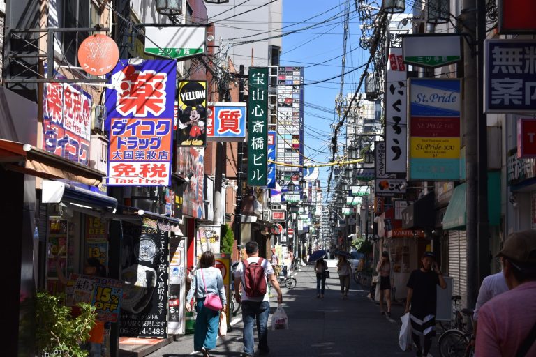 Bustling urban street in Osaka with colorful advertisements and pedestrians in daylight. — How to File Your Status in the Inc