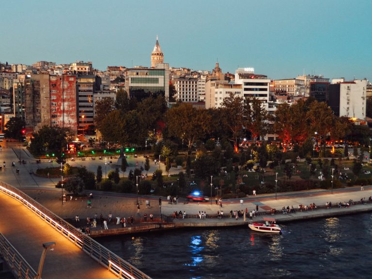 Scenic view of Istanbul's skyline featuring Galata Tower and bustling park at twilight along the waterfront. — How To Find Th