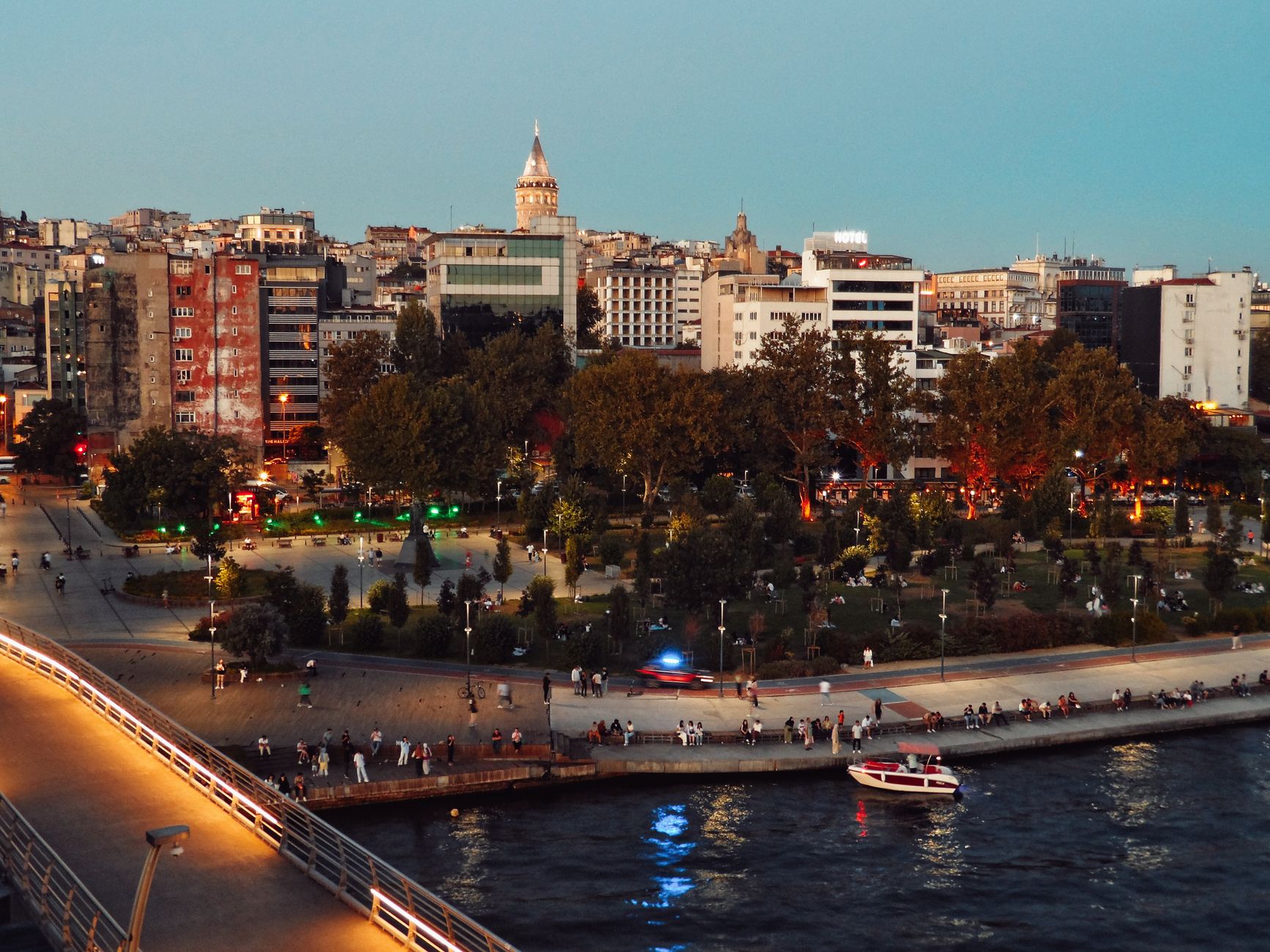Scenic view of Istanbul's skyline featuring Galata Tower and bustling park at twilight along the waterfront. — How To Find Th