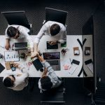 High angle view of colleagues collaborating around a conference table in a modern office setting. — How To Leave A Good Impre