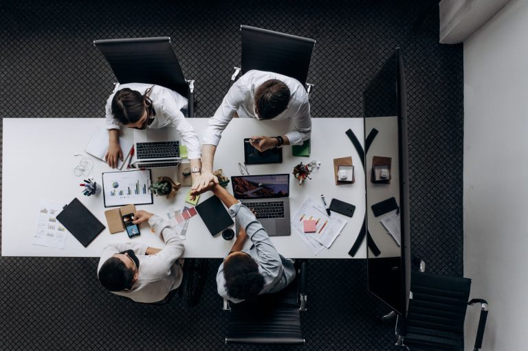 High angle view of colleagues collaborating around a conference table in a modern office setting. — How To Leave A Good Impre