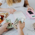 Two people handling cash and budgeting with a calculator and notebook at a table. — How to pay the NBPDCL bill online?