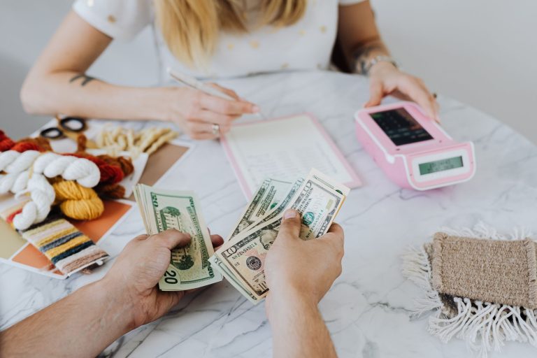 Two people handling cash and budgeting with a calculator and notebook at a table. — How to pay the NBPDCL bill online?
