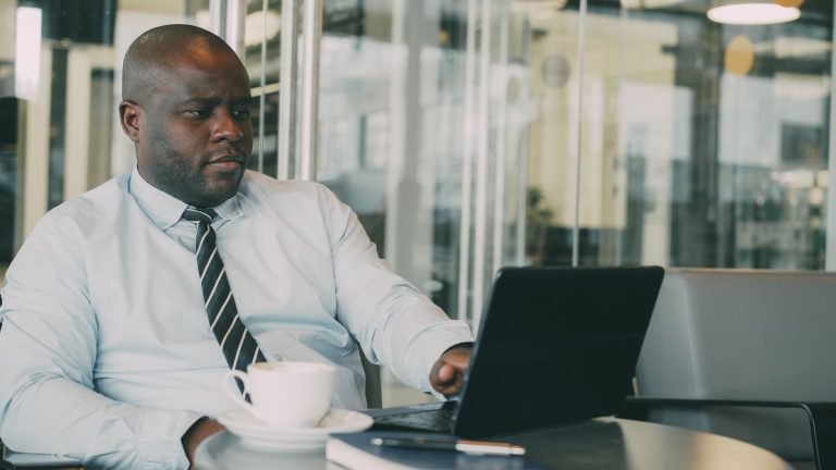 Focused businessman uses laptop in stylish cafe, sipping coffee. Perfect for business or lifestyle themes. — How to Pick the