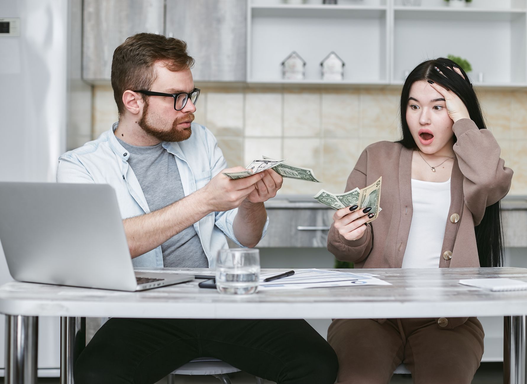 A shocked couple sitting at a table counting cash, illustrating financial surprise. — How VAT Bridging LoansWork And Why You
