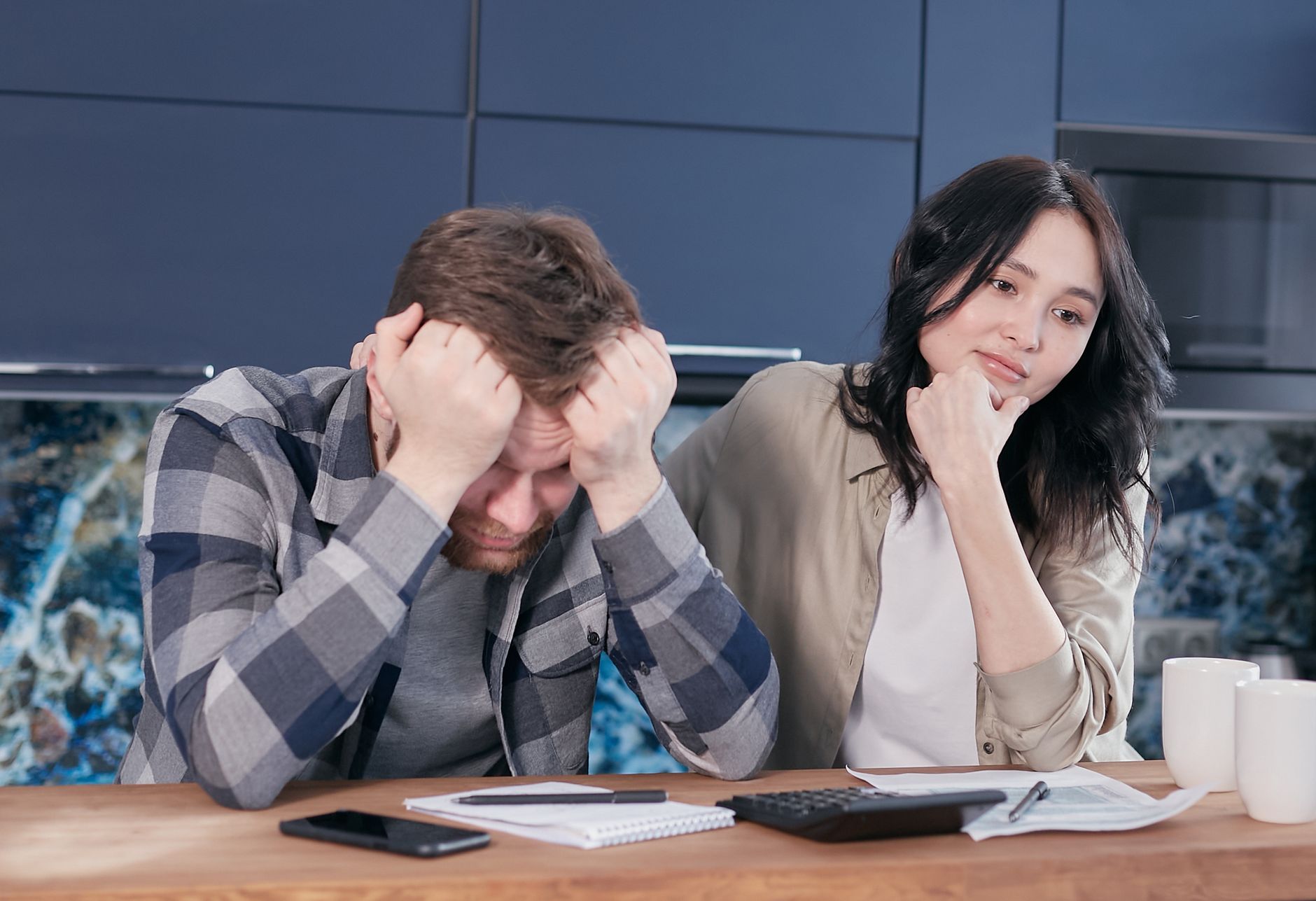 A couple looking worried while reviewing financial documents at a kitchen table. — Importance of Asset Allocation in Retireme